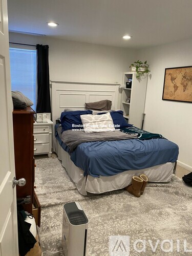 A bedroom with a bed, nightstand, and a plant.