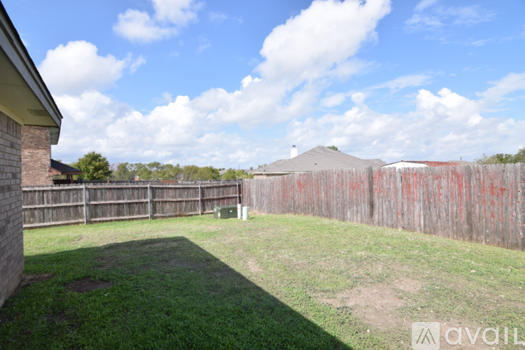 A backyard with a wooden fence and a grassy area.