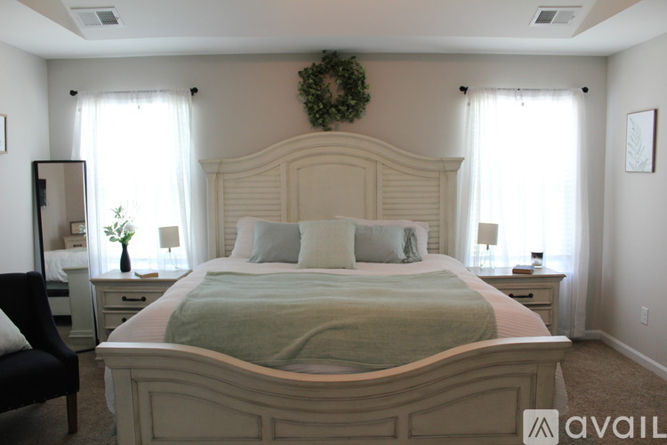 A bedroom with a large bed and a wreath on the headboard.