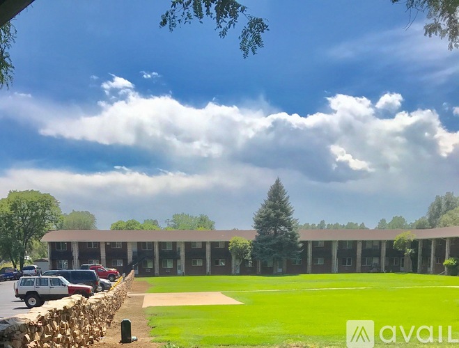 A large building with a green lawn in front and a cloudy sky above.