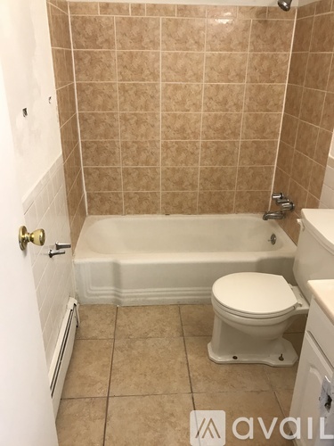 A bathroom with a toilet, tub, and tiled walls.