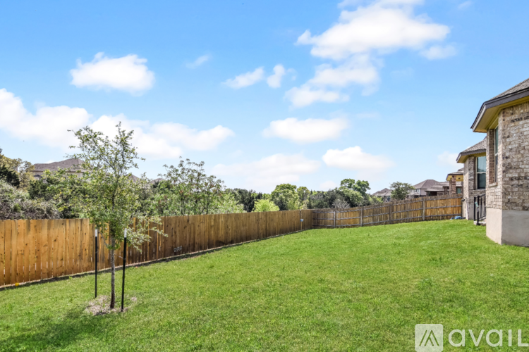 A grassy backyard with a wooden fence and a house in the background.
