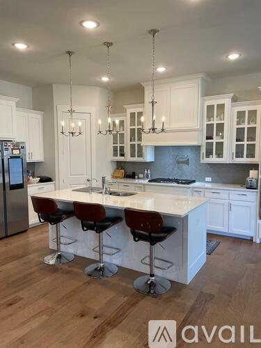 A kitchen with white cabinets and a central island with three stools.