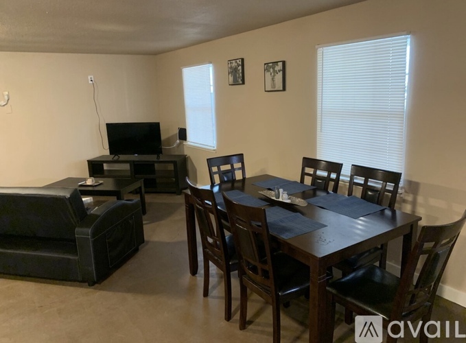 A living room with a black couch, a television, and a dining table with chairs.