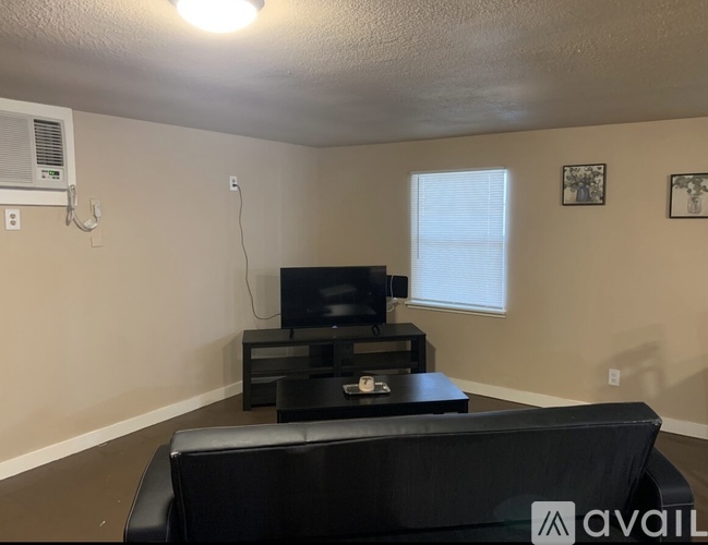 A living room with a black couch and a television.