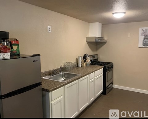 A kitchen with a stainless steel refrigerator and white cabinets.