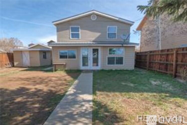 A house with a fence and a sidewalk in front.