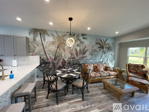 A living room with a black and white checkered table and a mural of palm trees on the wall.