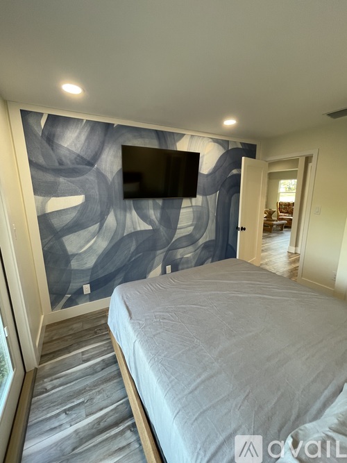 A bedroom with a large bed and a TV mounted on the wall.