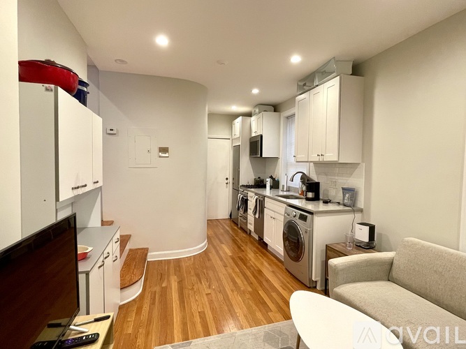 A modern kitchen with wooden floors and white cabinets.