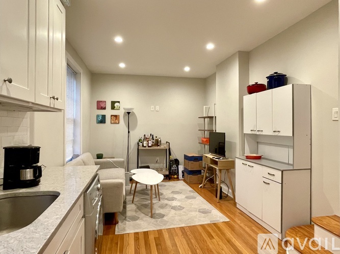 A modern kitchen with white cabinets and a wooden floor.