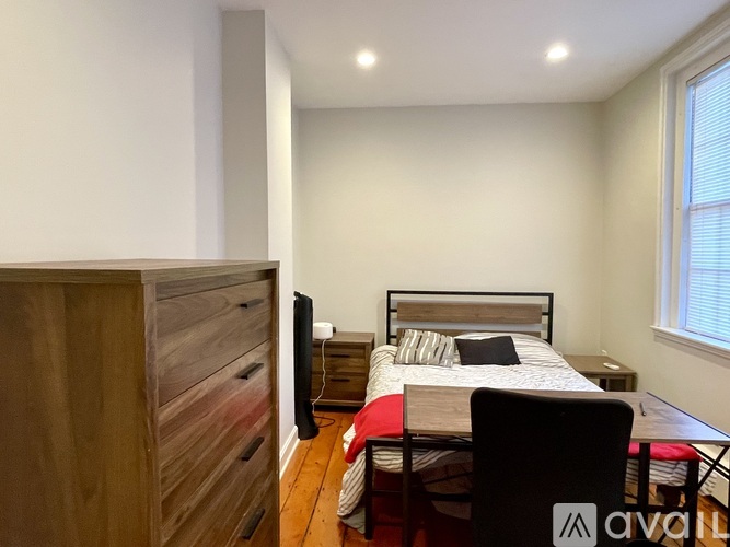 A bedroom with a bed, a chair, and a wooden wardrobe.