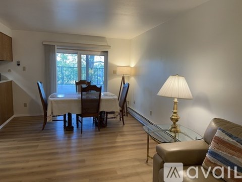 A living room with a couch, a dining table with chairs, and a lamp.