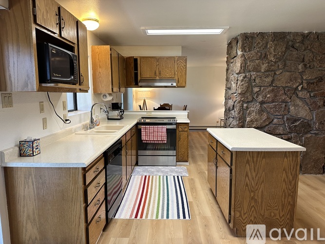 A kitchen with wooden cabinets and a stone wall.
