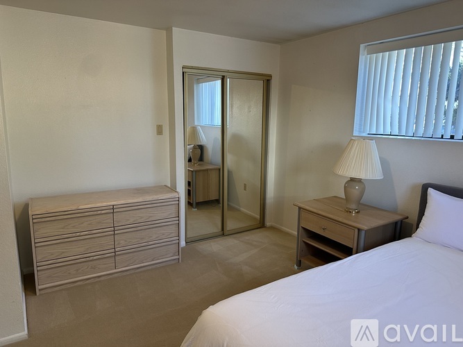 A bedroom with a bed, nightstand, and a dresser with a mirror above it.