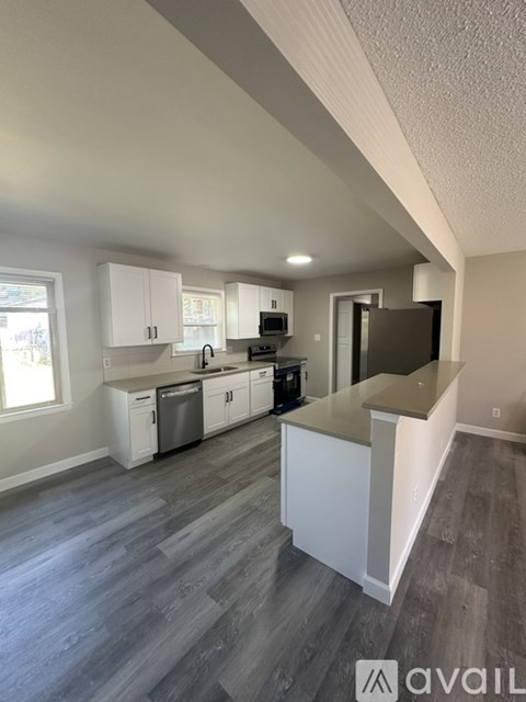 A kitchen with white cabinets and a grey floor.