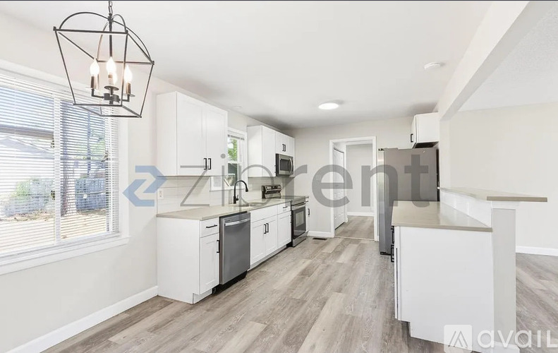 A kitchen with white cabinets and a grey floor.