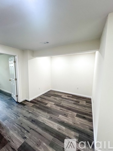 A room with wooden flooring and white walls.