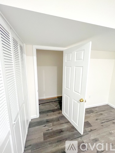 A room with a white door and wooden flooring.