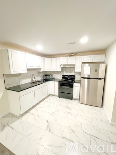 A kitchen with white cabinets and a marble floor.