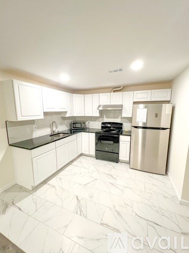 A kitchen with white cabinets and a marble floor.