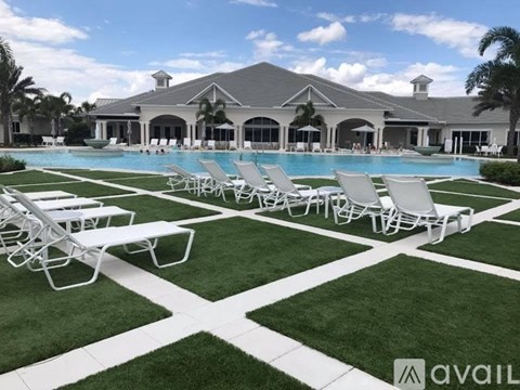 A large house with a pool and lawn chairs in front.
