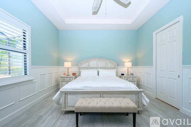 A bedroom with a large bed and a window with blinds.