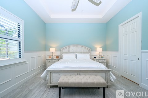 A bedroom with a large bed and a window with blinds.