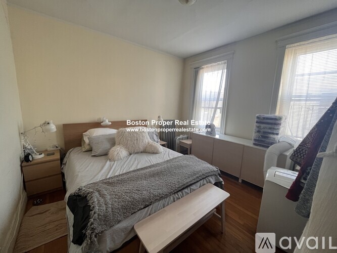 A bedroom with a bed, nightstand, and window.