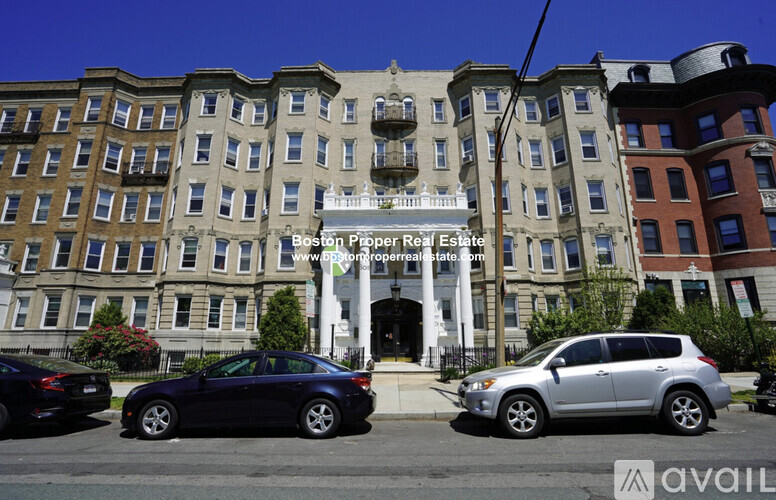 A street view of a building with cars parked in front and a sign that says "Boston Proper Real Estate".