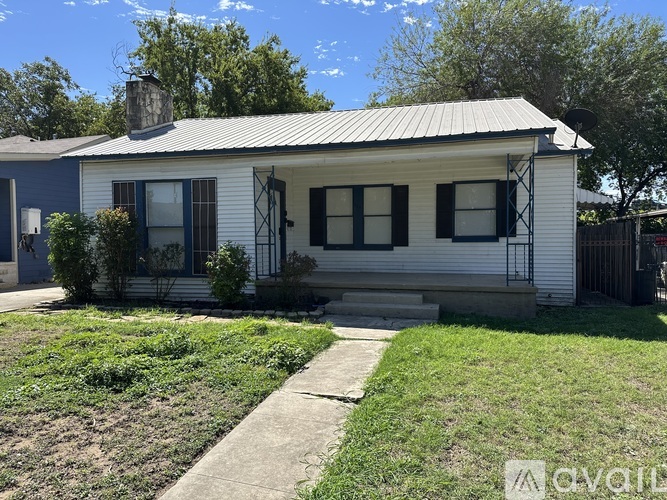 A house with a blue roof and white walls is for sale.