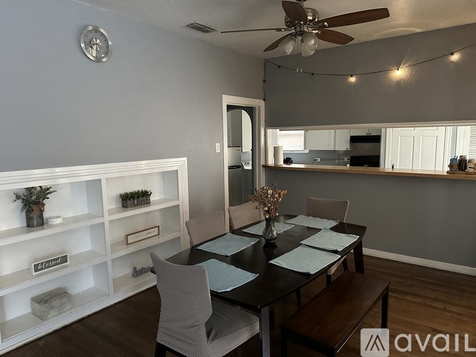 A dining room with a table set for four and a ceiling fan.