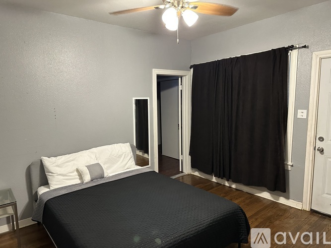 A bedroom with a bed, a ceiling fan, and a door leading to a bathroom.
