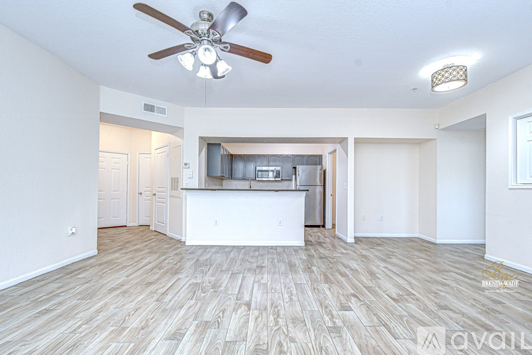 A spacious living room with a kitchen in the background and hardwood floors.
