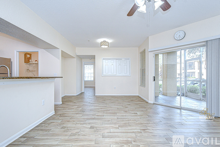 A spacious living room with a ceiling fan and a clock on the wall.