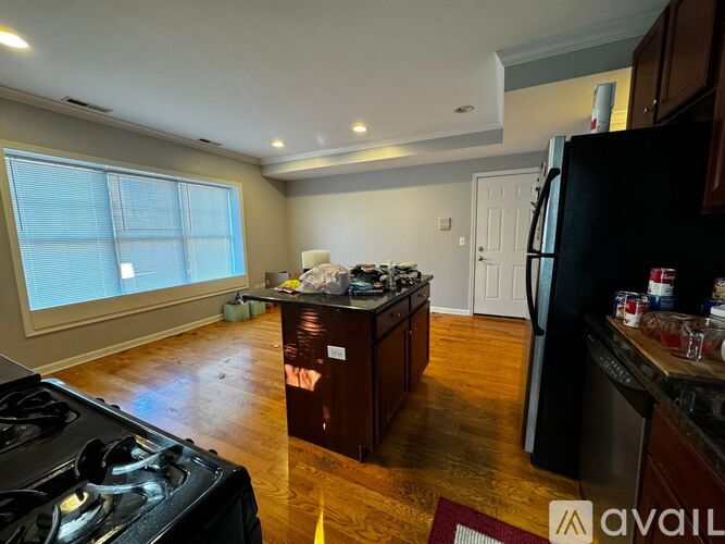 A kitchen with a black stove top oven and wooden floors.