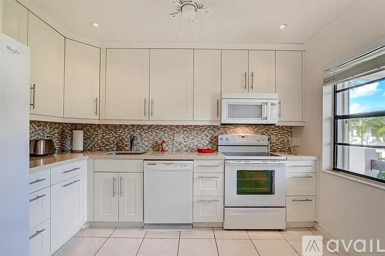 A kitchen with white cabinets and appliances.