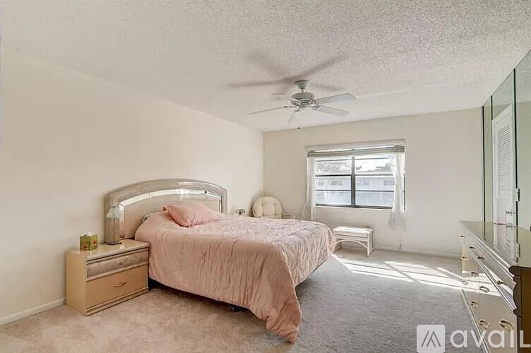 A bedroom with a bed, nightstand, and window.