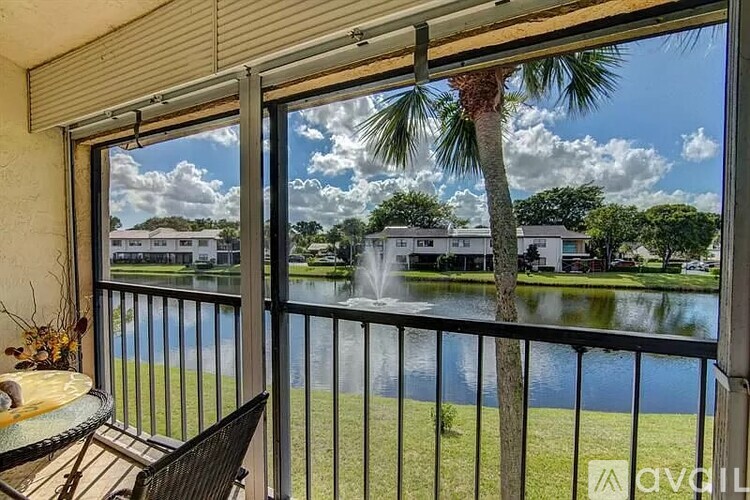 A balcony with a table and chairs overlooking a pool and a fountain.