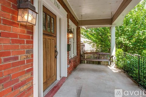 A porch with a wooden door and a brick wall.