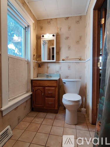 A bathroom with a toilet, sink, and mirror.