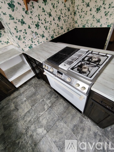 A stove is installed in a kitchen with a floral wallpaper.
