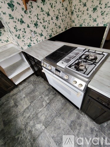 A stove is installed in a kitchen with a floral wallpaper.
