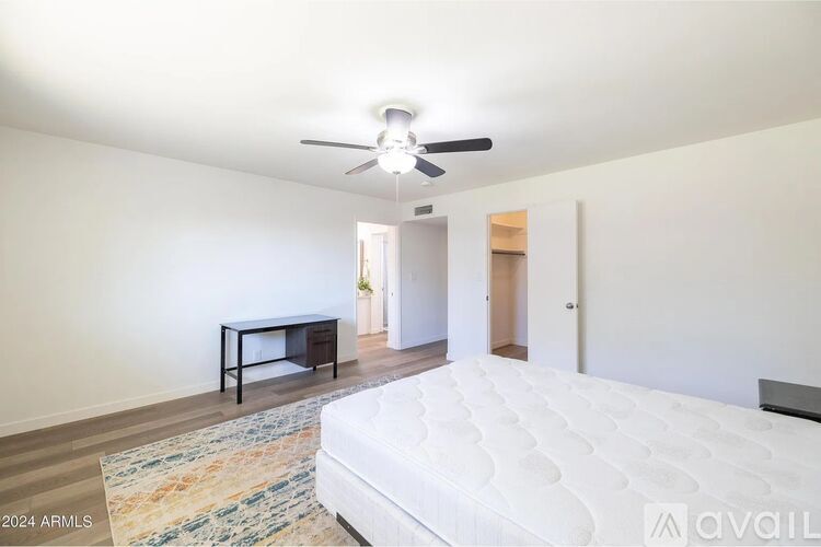 A bedroom with a white bed, a ceiling fan, and a bench.