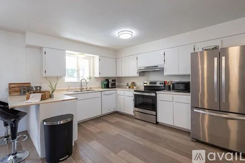A modern kitchen with a stainless steel refrigerator and wooden flooring.