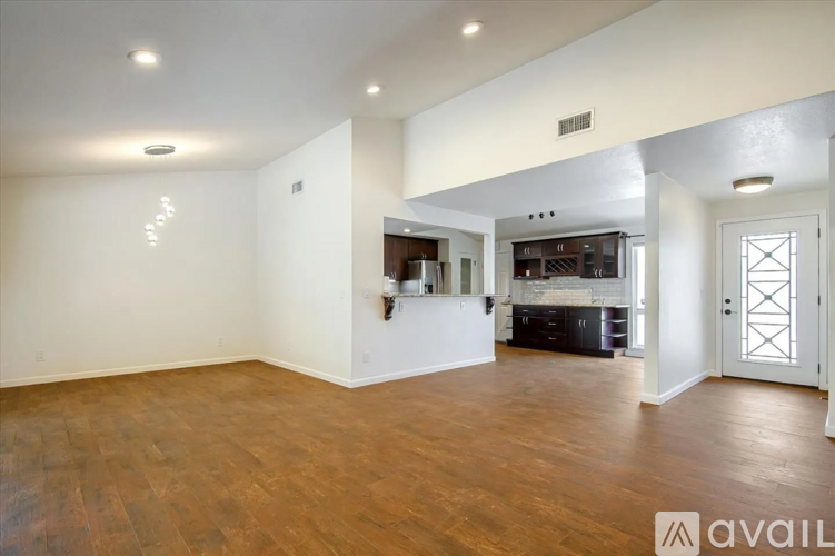 A spacious living room with hardwood floors and a large mirror on the wall.