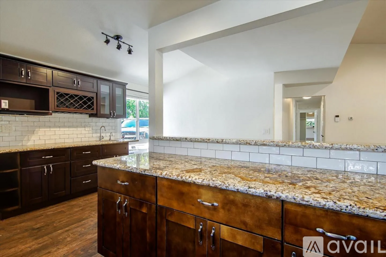 A kitchen with dark wood cabinets and a granite countertop.