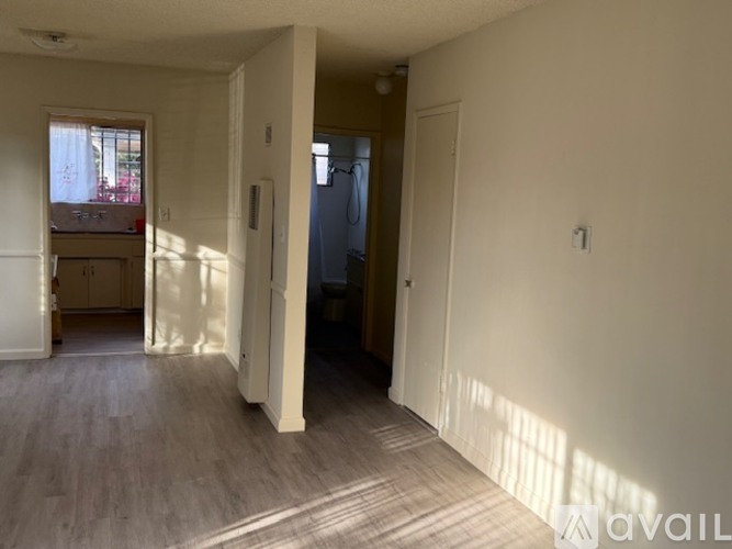 A room with a doorway leading to another room and a window letting in sunlight.