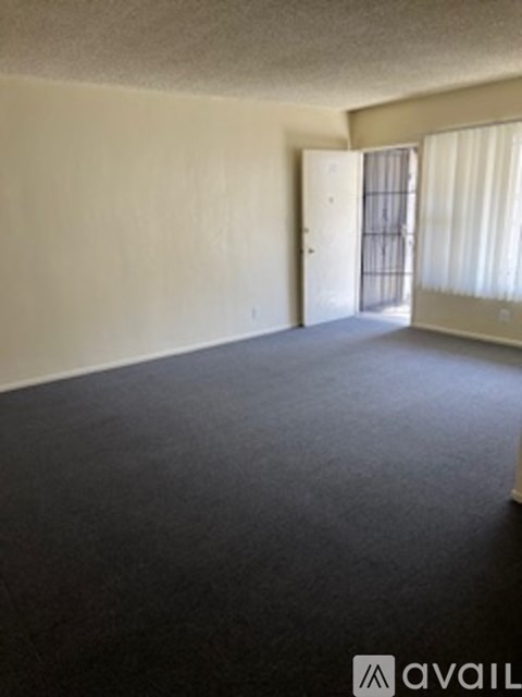 A room with a doorway leading to another room and a window letting in sunlight.