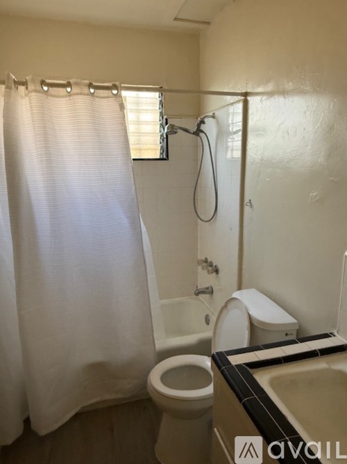 A white bathroom with a toilet, sink, and shower.